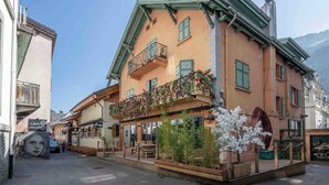 A building with a balcony adorned with flowers, a sign for 'Psyllon', and a restaurant named 'Café-Horn'. - Spacious loft on pedestrian street with views (Chamonix-Mont-Blanc)