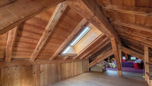 An attic room with wooden beams, a skylight, and a bed with pillows. - Spacious loft on pedestrian street with views (Chamonix-Mont-Blanc)