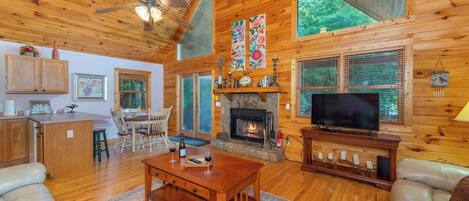 A spacious living room with a fireplace, a television, and a dining area with wooden furniture.