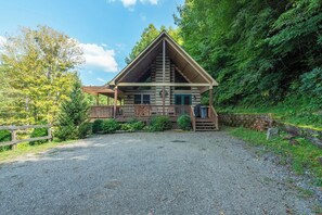 En stuga med en träfasad, en veranda och en grusuppfart.