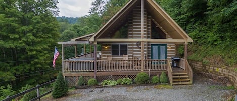 Eine Hütte mit Veranda, einer Flagge und Blick auf den Wald.