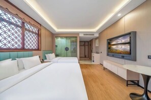Une chambre d’hôtel avec deux lits, une télévision, un bureau et une vue sur la ville.