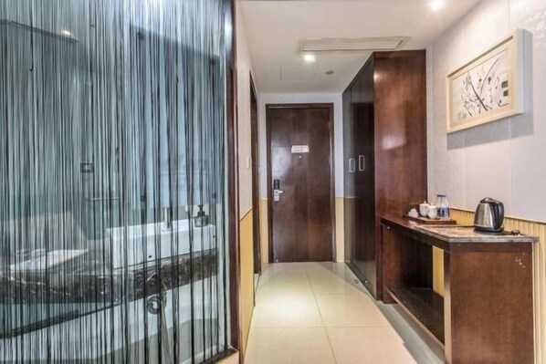 A hotel corridor with a glass partition, wooden doors, a small table with a kettle, and a framed picture on the wall. - Chonpines Hotel (Suzhou Hanshan Temple Shantang Street Liuyuan Store) (Suzhou)