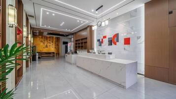 A modern hotel lobby with a reception desk, a clock, and a seating area.