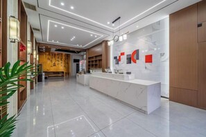 A modern hotel lobby with a reception desk, a clock, and a seating area. - Chonpines Hotel (Suzhou Hanshan Temple Shantang Street Liuyuan Store) (Suzhou)