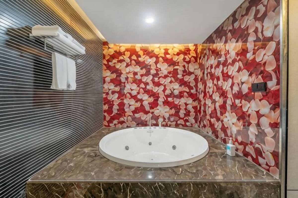 A bathroom with a large bathtub, a marble countertop, and a wall with a floral pattern.