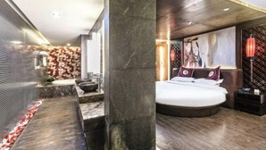 Une chambre moderne avec un grand lit, une salle de bain dotée d’un plan de toilette en marbre et un mur décoratif.
