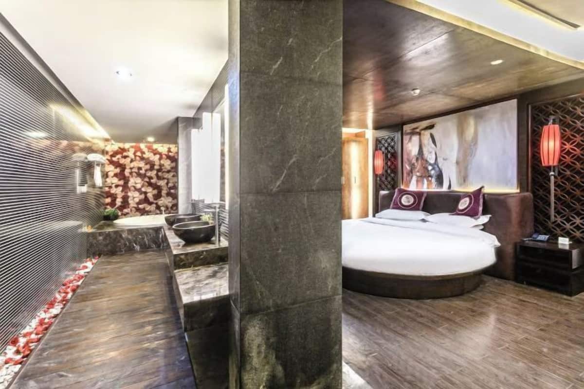 A modern bedroom with a large bed, a bathroom with a marble countertop, and a decorative wall.