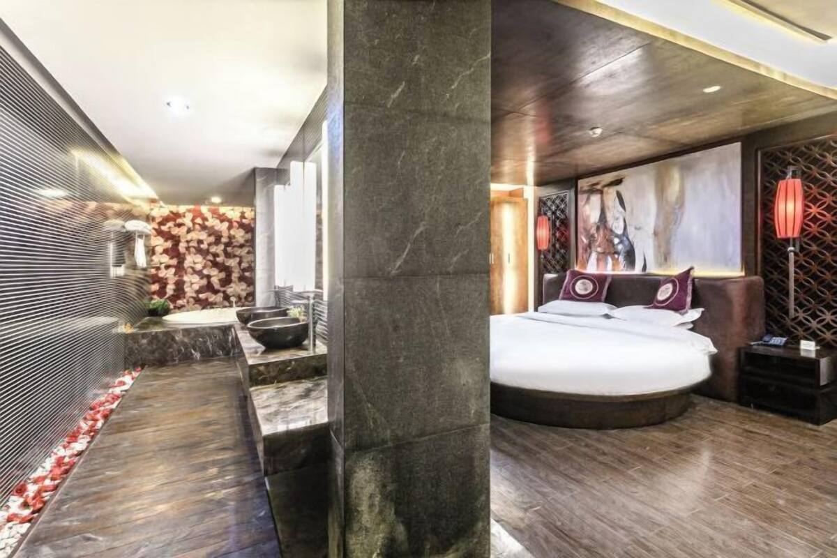 A modern bedroom with a large bed, a bathroom with a marble countertop, and a decorative wall.