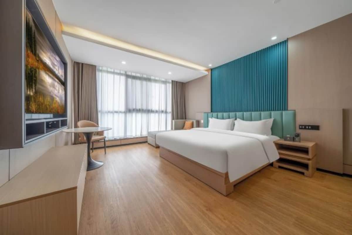 A modern hotel room with a large bed, a desk, and a TV.