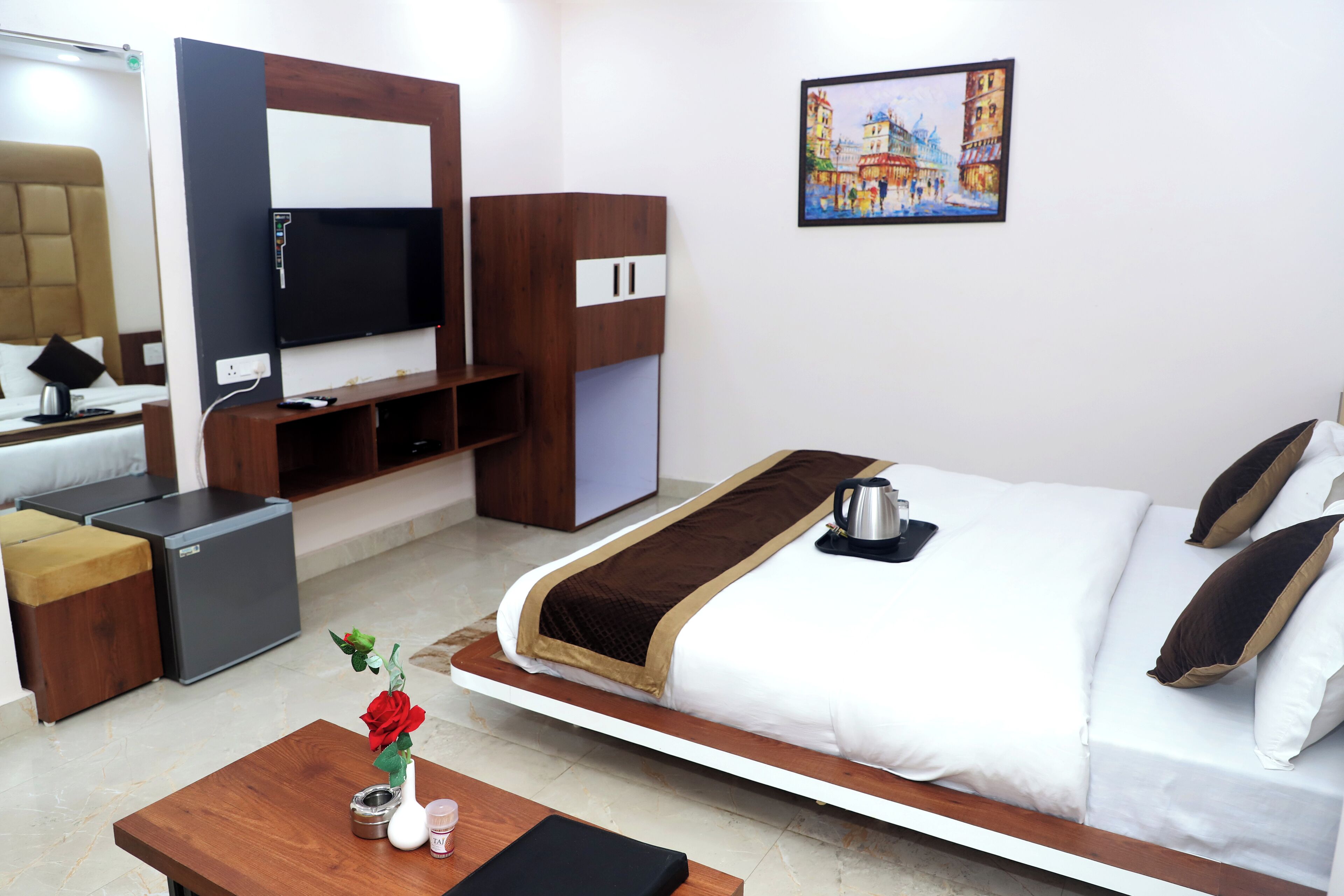 Una habitación de hotel moderna con una cama, un televisor, una cafetera y un cuadro en la pared.