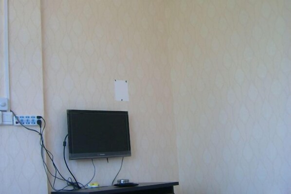 A television mounted on a wall with a power strip and cables.