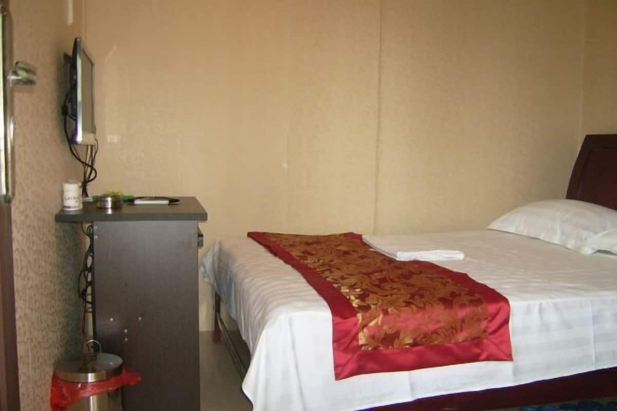 Ein Hotelzimmer mit einem Bett, einem Schreibtisch mit Computer und einer Mülleimer.