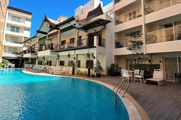 Un hotel con piscina, mobiliario exterior y balcones.