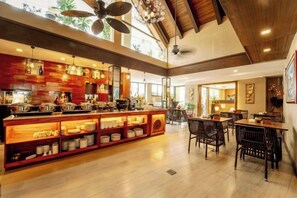 Un vaste espace dédié à la salle à manger, doté d’un plafond haut et d’un bar central agrémenté d’étagères et d’équipements de cuisine.