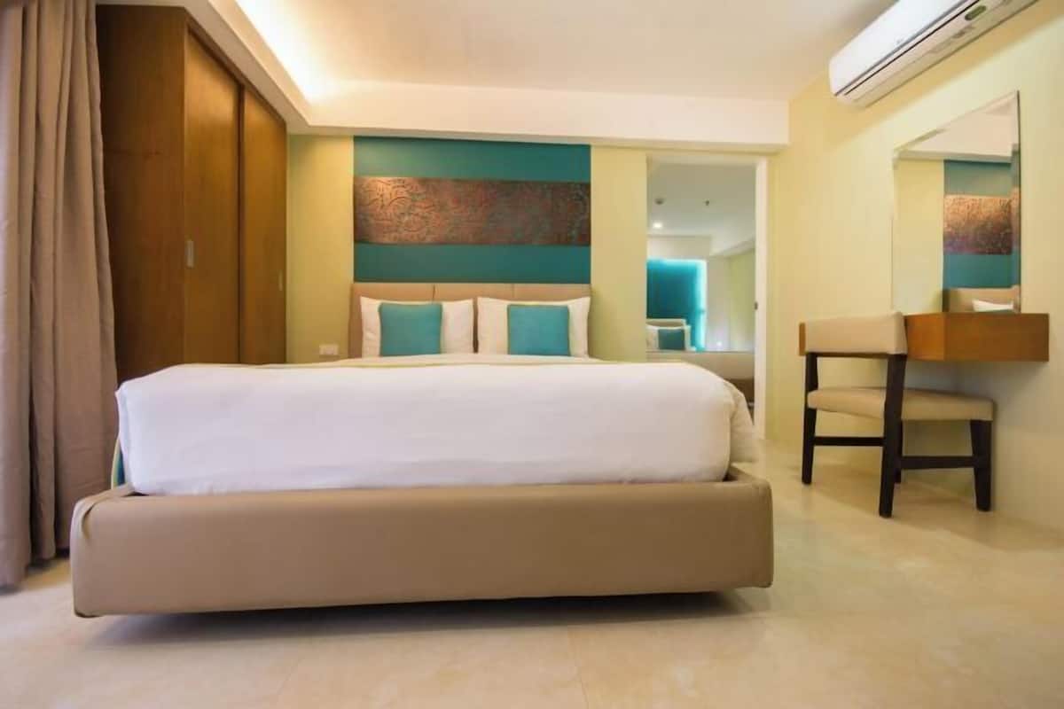 Une chambre d’hôtel avec un grand lit, une chaise, un miroir et une porte.