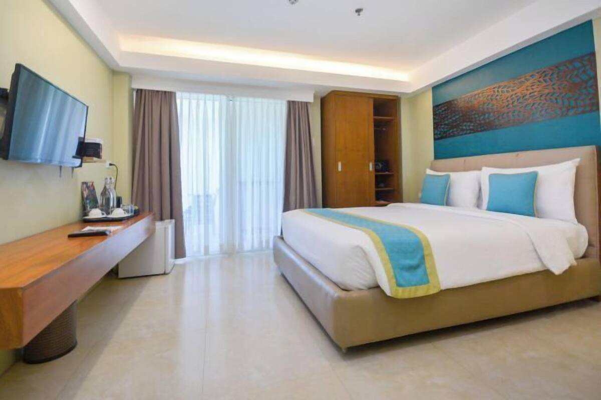 Une chambre d’hôtel équipée d’un lit, d’un bureau, d’une télévision et d’une armoire.