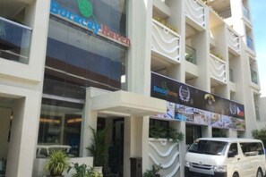 Un immeuble à plusieurs étages, avec une enseigne indiquant « Boracay Haven », et un fourgon blanc garé devant.