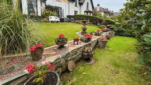 A well-maintained garden with a stone pathway leading to a white house with a steeply pitched roof. - 4 bedroom accommodation in Aberfeldy (Aberfeldy)