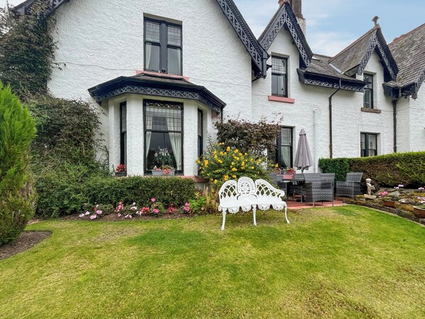 A white house with a bay window, a garden with a white bench, and a statue. - 4 bedroom accommodation in Aberfeldy (Aberfeldy)