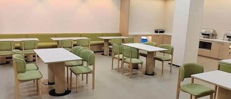 A dining area with booths and tables, equipped with chairs and a coffee machine.