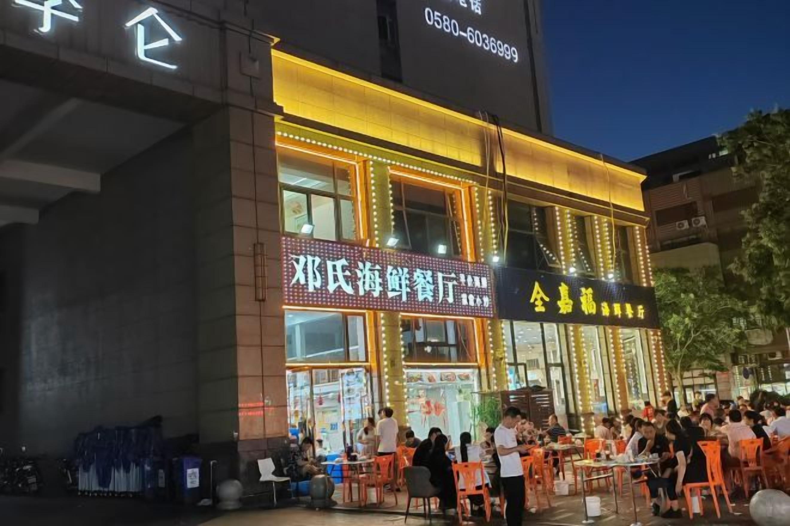 A building with illuminated signage and outdoor seating, suggesting a dining establishment.