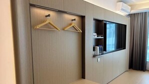 Een moderne hotelkamer met een inbouwkleerkast, een flatscreen televisie en een bank.