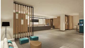 Un moderno vestíbulo de hotel con una recepción, una zona de estar y una cocina al fondo.