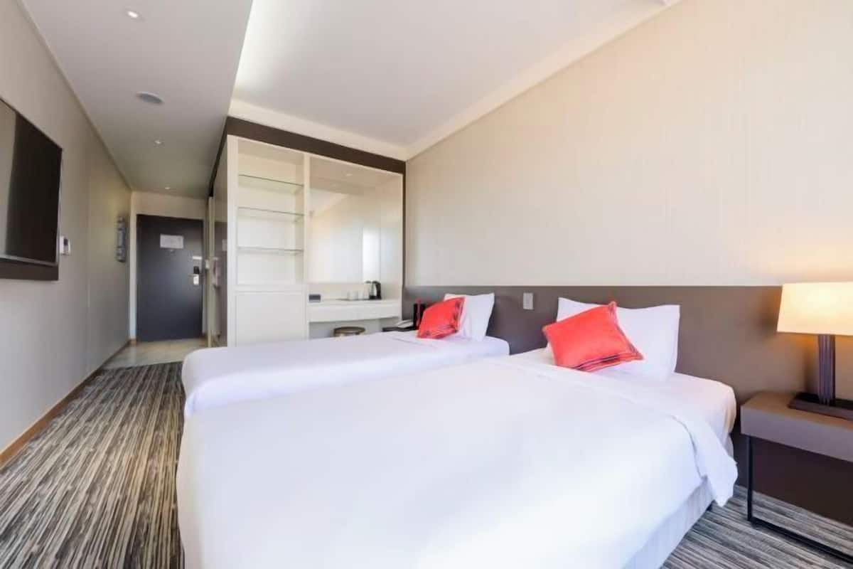 Une chambre d’hôtel avec un grand lit, une table de chevet, un miroir et une vue sur le couloir.