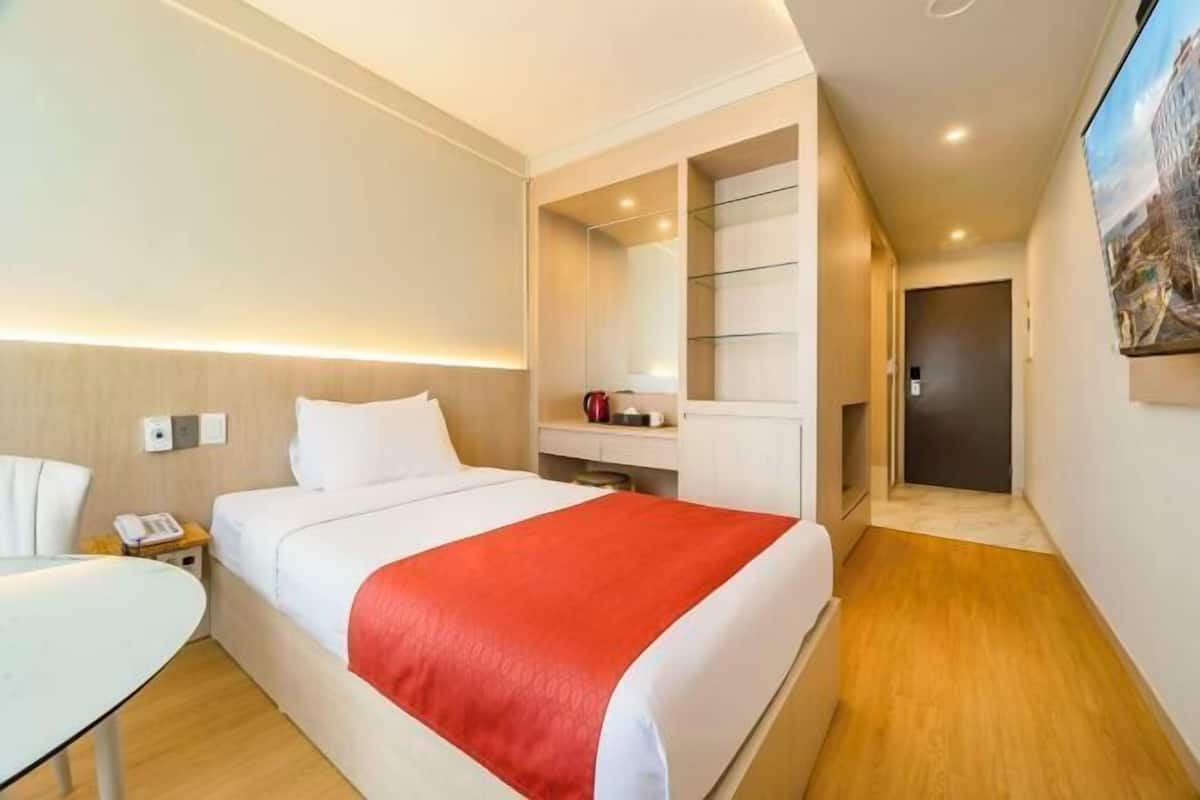 Une chambre d’hôtel avec un lit, une table de chevet et un petit bureau.