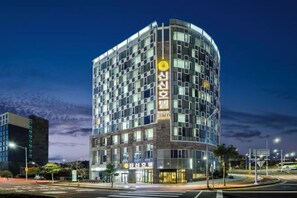 A multi-story hotel with a modern design, featuring a prominent entrance and a large sign. - Shin Shin Hotel Jeju Worldcup (Seogwipo)