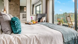 A modern hotel room with a large bed, a dining area with breakfast, a large mirror, and a balcony with a view. - 5 bedroom accommodation in Totland (Totland)