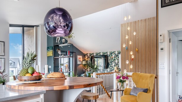 A modern kitchen with a central island, wooden bar stools, a yellow armchair, and a decorative hanging light fixture. - 5 bedroom accommodation in Totland (Totland)