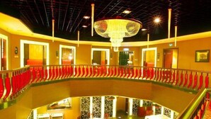 Un vestíbulo de hotel con un atrio central, una araña y asientos rojos a lo largo de las paredes.