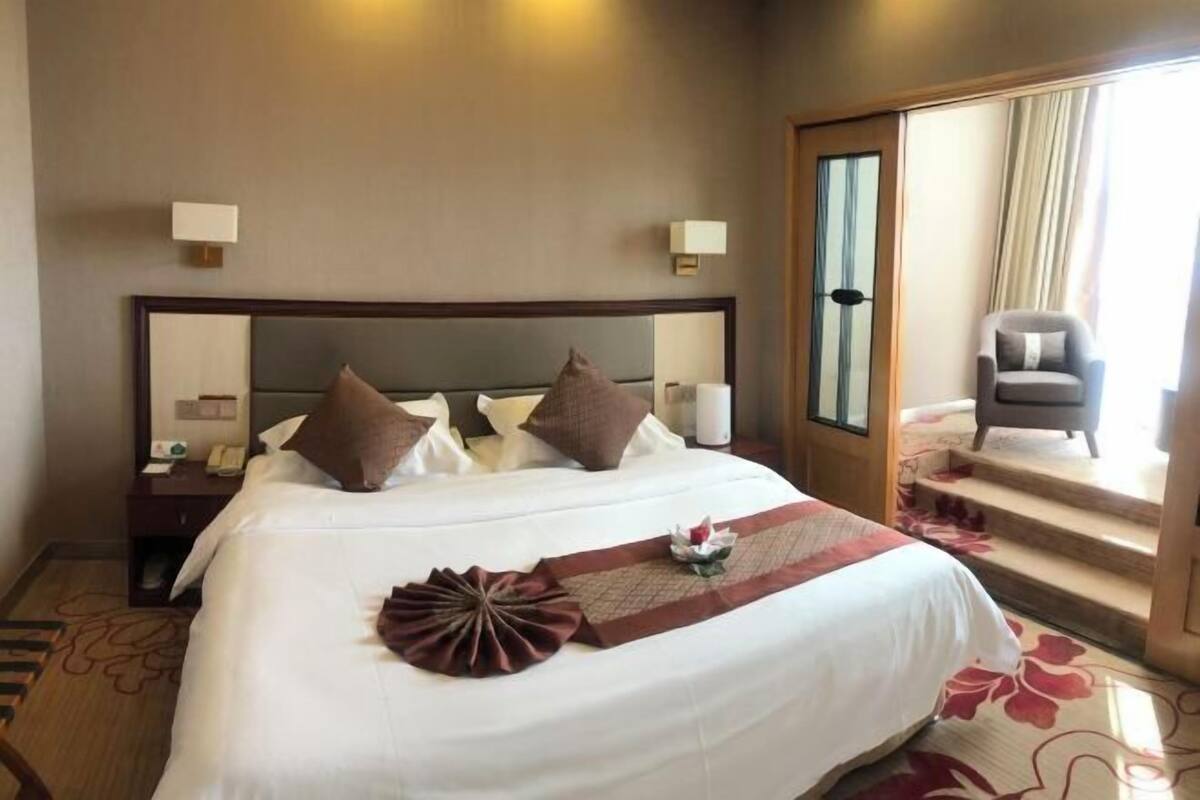 Une chambre d’hôtel avec un grand lit, une table de chevet, une chaise et une vue sur l’extérieur.