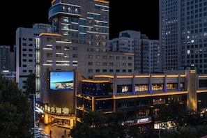 Ein Hochhaus-Hotel mit mehreren Etagen, einer auffälligen digitalen Werbeanzeige und einer gut beleuchteten Fassade.
