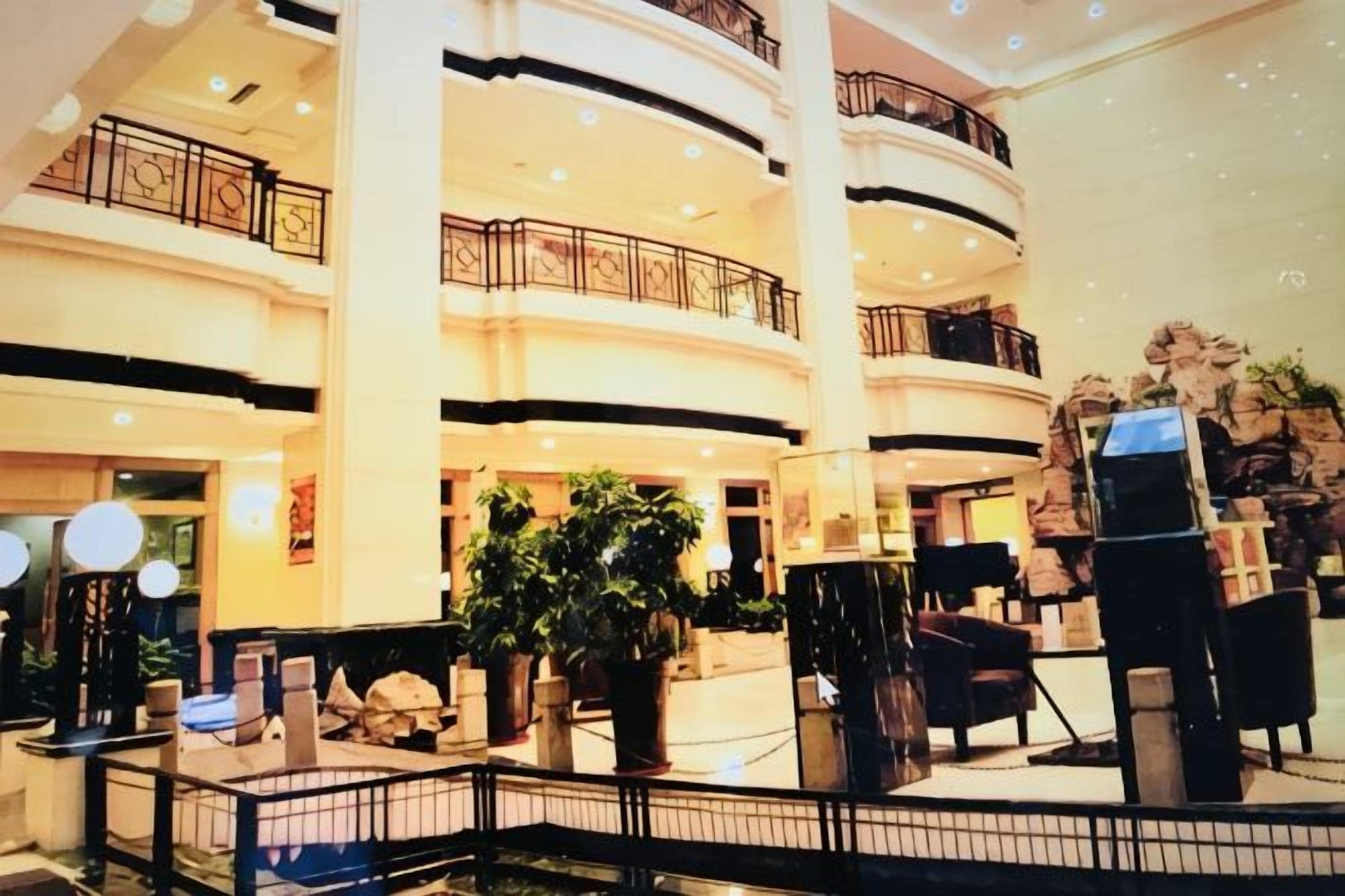 A multi-level atrium with balconies, potted plants, and a central seating area.