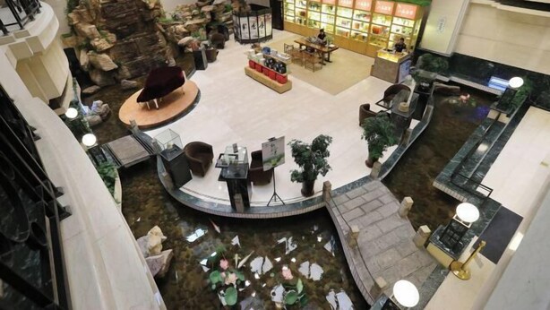 Un amplio atrium con un área de estar central, una fuente de agua y un restaurante.
