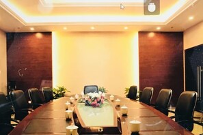 Un salón de conferencias con una larga mesa, sillas y un centro de mesa con flores.
