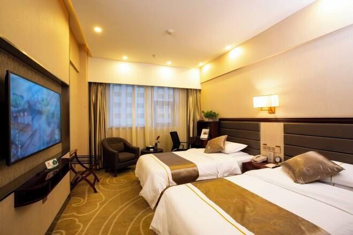 Une chambre d’hôtel avec deux lits, une télévision, un bureau avec une lampe et une chaise.