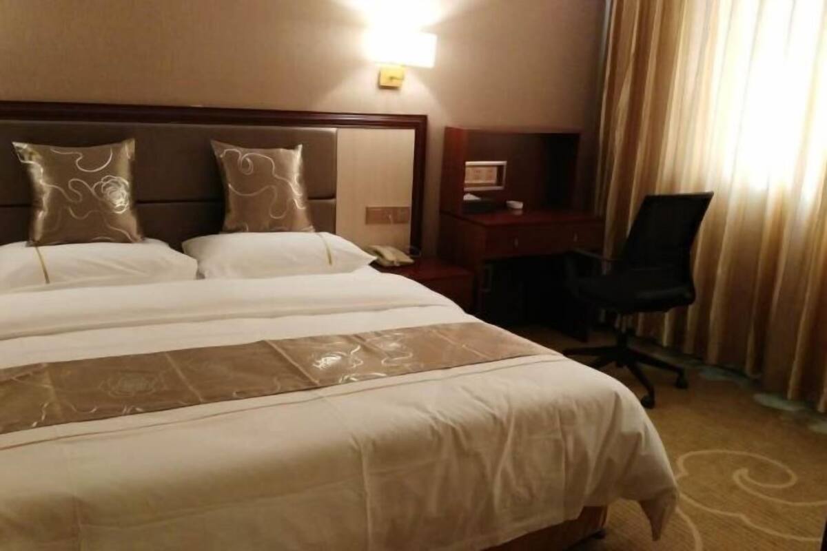 Une chambre d’hôtel avec un grand lit, un bureau, une chaise et un téléphone.