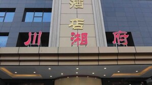 Un hotel con una fachada moderna, que cuenta con amplios ventanales y un letrero llamativo con caracteres chinos.