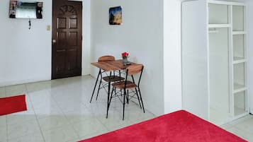 A room with a wooden dining table and chairs, a red carpet, a white cabinet, and a door with a decorative panel.