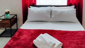 A neatly made bed with white linens and pillows, a red throw blanket, and a folded white towel on the bed. - Reddoorz @ Rio Bella Lacson St. Bacolod (Bacolod)