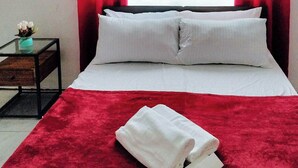 A neatly made bed with white linens and pillows, a red throw blanket, and a folded white towel on the bed. - Reddoorz @ Rio Bella Lacson St. Bacolod (Bacolod)