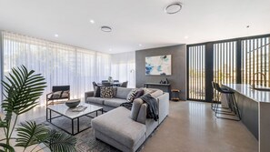 Relax in this stylish living space with a plush sofa, glass dining table, and modern coffee table.