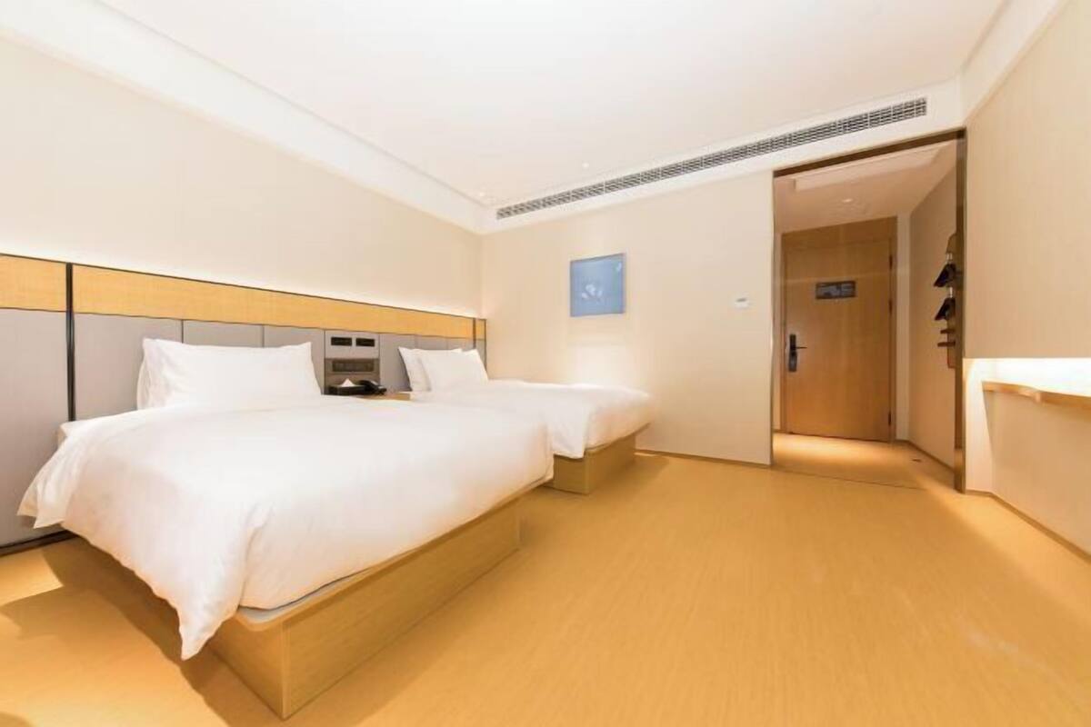 A hotel room with a large bed, a smaller bed, a bedside table, and a wardrobe.