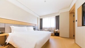 A hotel room with a large bed, bedside tables, a desk, and a window with curtains. - JI Hotel (Shanghai World Expo Area Yaohua Road) (Shanghai)