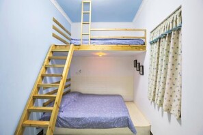 A bunk bed room with a wooden ladder, a window with curtains, and a wall-mounted light fixture.