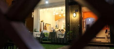 An outdoor seating area with tables and chairs, a brick wall, and a building entrance.